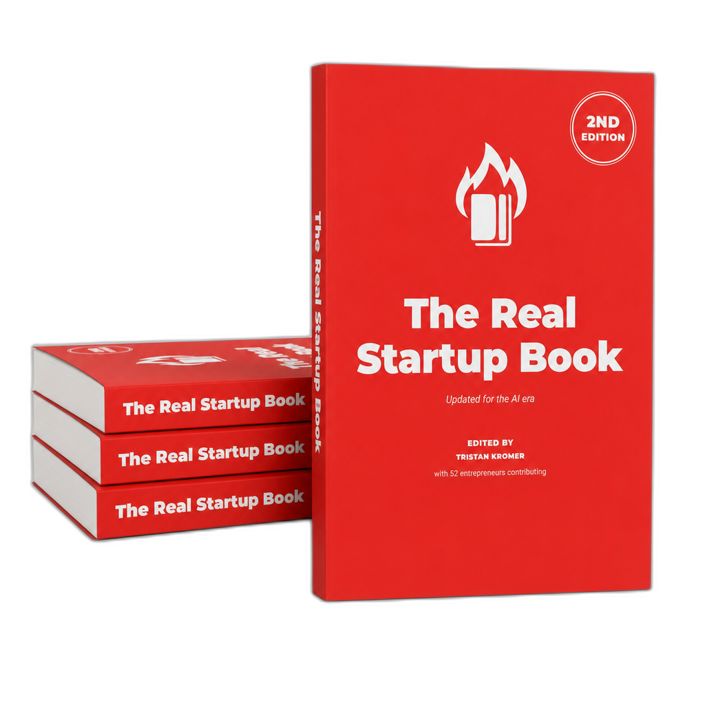 The 2nd edition of The Real Startup Book — a red paperback edited by Tristan Kromer, with three more copies stacked behind it.